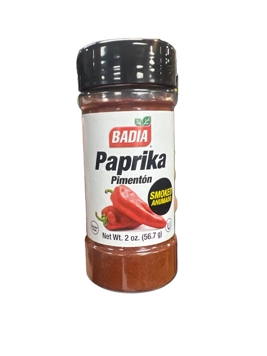 Hand holding a jar of Badia Paprika in a grocery store aisle.