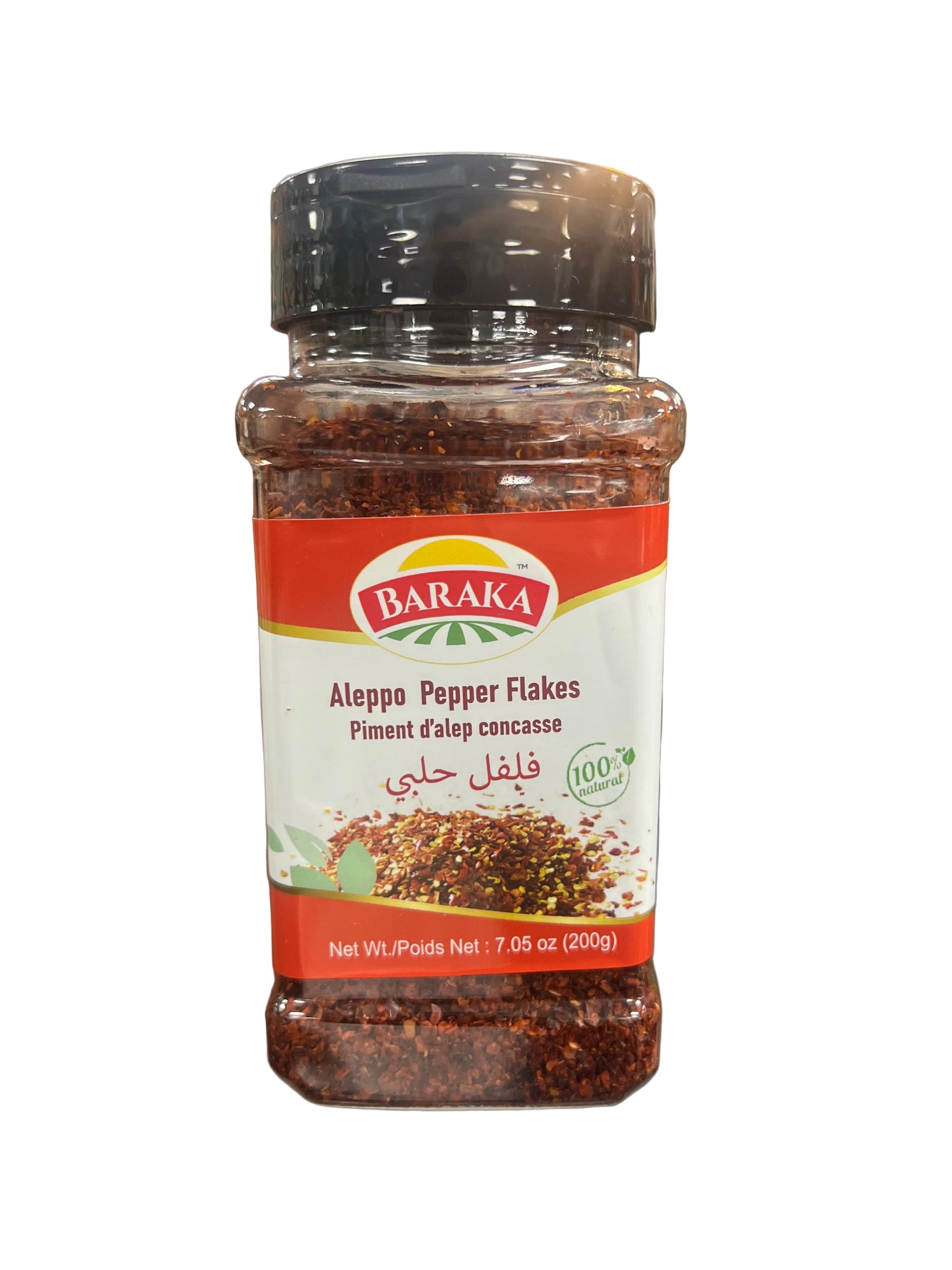 Jar of Baraka Aleppo Pepper Flakes held in a hand with a blurred store background
