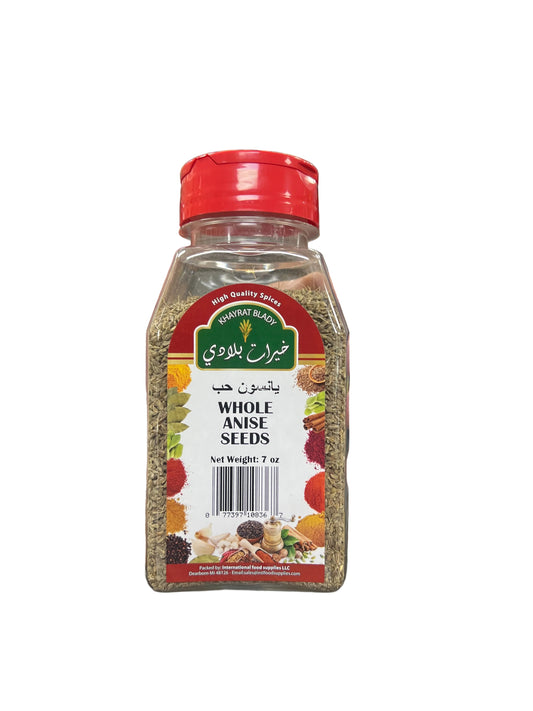 Hand holding a bottle of whole anise seeds in a grocery store aisle.